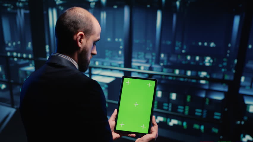 Network engineer doing system check on green screen, using tablet showing chroma key display with isolated copyspace in server room. IT technician working with cyber security. Tripod shot. Royalty-Free Stock Footage #1100246681