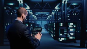 Datacenter engineer inspecting working server computers with web information on tablet, future digitalization. Modern IT administrator running diagnostics on networking connection. Tripod shot. - Powered by Shutterstock - Get 15% off with code: PIKWIZARD15