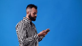 4k video of one man scrolling messenger and smiling over blue background.