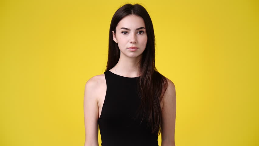 4k video of one girl looks around and showing silence sign over yellow background. Royalty-Free Stock Footage #1100249351