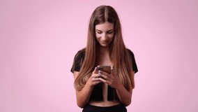 4k video of one girl typing text and looking up laughingly on pink background.