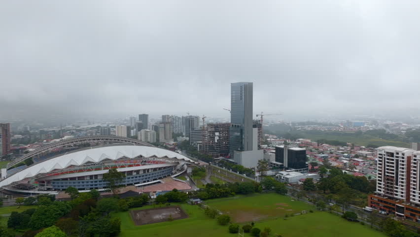 Aerial footage of famous football stadium, park and surrounding buildings in city. Estadio Nacional de Costa Rica in La Sabana Park. San Jose, Costa Rica