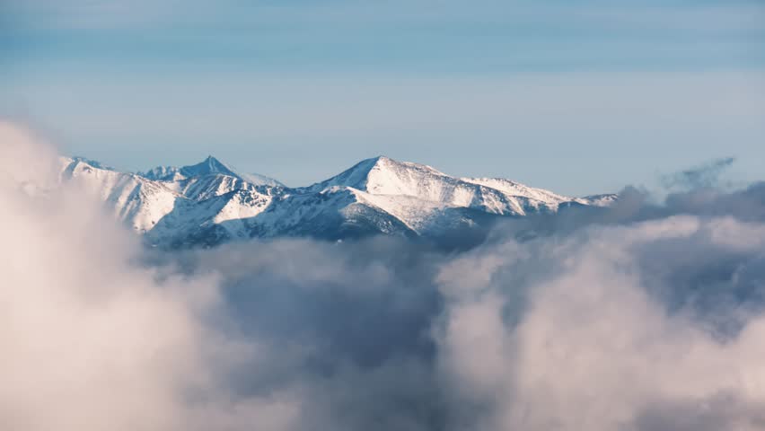 Long shot of snow-capped mountain peaks, shrouded in clouds Royalty-Free Stock Footage #1100252953