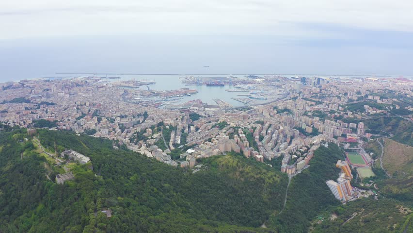Inscription on video. Genoa, Italy. Central part of the city, aerial view. Ships in the port. Appears from the sand, Aerial View
