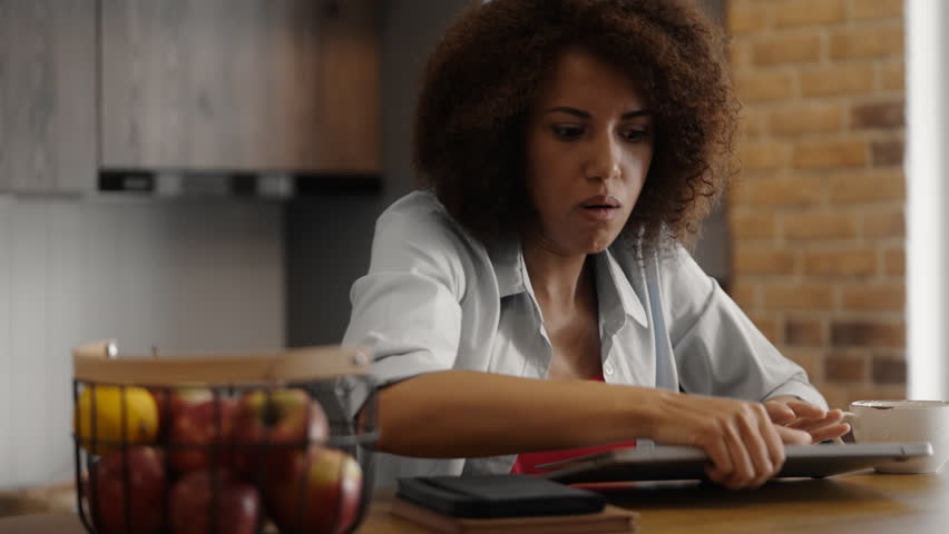 Young woman typing on laptop, drinking morning coffee in a hurry, late for work
