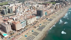 Aerial drone footage of the beautiful beach front of the coastal town of  Fuengirola in Malaga Spain Costa Del Sol, showing the sandy beach, hotels and apartments on a sunny day in the summer time
