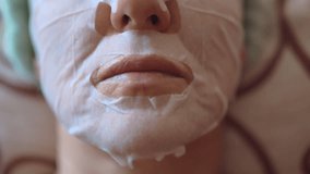 Anti-wrinkles and anti-aging procedures at home, middle-aged woman relaxing on the sofa with applied sheet face mask, collagen and vitamins for human skin care, rejuvenation of middle-aged woman face - Powered by Shutterstock - Get 15% off with code: PIKWIZARD15