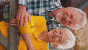 Vertical video portrait of Vertical video of smiling senior couple leaning on gate outside dream cottage - shot in slow motion - Powered by Shutterstock - Get 15% off with code: PIKWIZARD15
