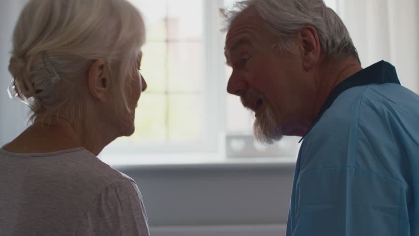 Close up of worried retired senior couple sitting on bed at home discussing problem together with man comforting woman - shot in slow motion | Shutterstock HD Video #1100255643