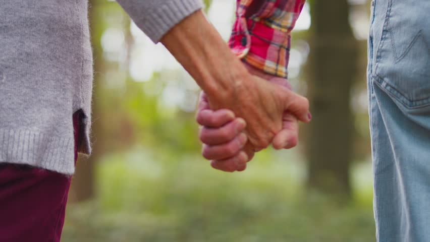 Close up rear view of senior couple holding hands on walk in beautiful countryside enjoying nature together - shot in slow motion | Shutterstock HD Video #1100255739