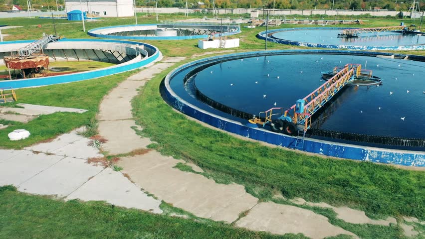 Aerial. round tank water treatment plant processing removing contaminants from wastewater or sewage | Shutterstock HD Video #1100259433