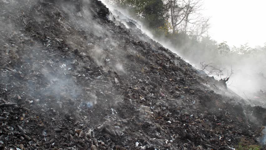 Garbage and fire burn in landfill.
Occurs smoke, toxic cause of air pollution, environmental damage and global warming.
 | Shutterstock HD Video #1100260785