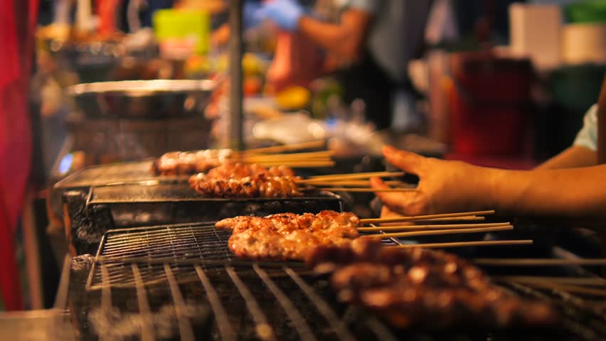 Local Asian Street Food. Chef Cooking Chicken Satay on Fire Bbq Grill at Night Market in Phuket Old Town. High Quality Cinematic 4K Slowmotion Thai Cuisine Footage. Thailand. Royalty-Free Stock Footage #1100264719