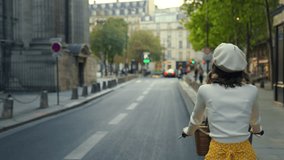 A young girl riding a yellow bicycle through the streets of Paris