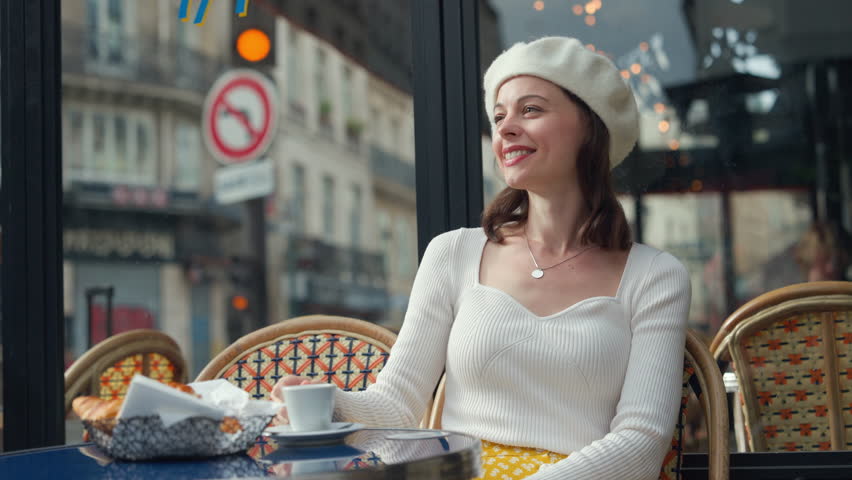 Smiling woman drinking coffee at a table in a cafe | Shutterstock HD Video #1100264881