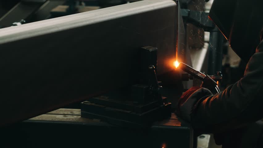 Close-up of a welder in a protective mask works with metal steel and iron with a welding machine in a factory, bright sparks and flashes in slow motion. Welding device | Shutterstock HD Video #1100264987
