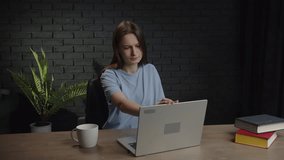 A sleepy woman drinks coffee from a cup to cheer herself up and finish a work project. Video of a woman yawning while working on a laptop.
