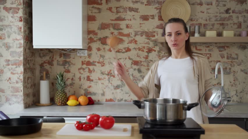 Young woman is dancing in the kitchen room. She cooks soup and relaxes in her free time on weekends.  | Shutterstock HD Video #1100276235