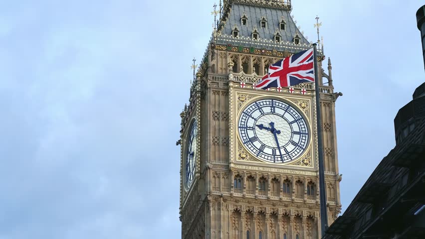 LONDON, UK - Feb 5, 2023: British flag in front of Big Ben tower clock, Palace of Westminster, Houses of Parliament in London. Famous English tourism destination, iconic landmark, travel in England.