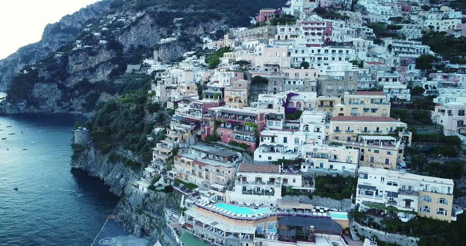 Aerial Drone View of Amalfi coast, Flying along the old town of Amalfi coast passing a waterway shore port, docks and boats in the sea. Postitano, Italy. Beautiful mountain destination. Cloudy day. | Shutterstock HD Video #1100279921