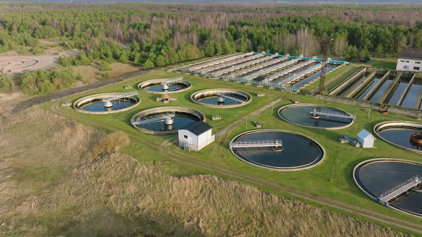Aerial establishing view of water basins at sewage treatment plant, ponds for recycling dirty wastewater, recycle system technology, waste management theme, drone shot moving backward, tilt up | Shutterstock HD Video #1100287529