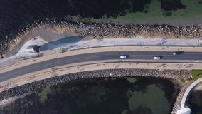 A bridge in the middle of the sea. The road with the car. Video from a drone. People walking on the bridge. The road in the sea. Traffic on the bridge. Beautiful shadows.