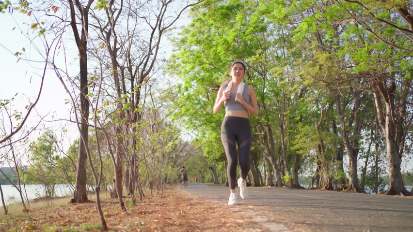 Asian fit sport woman running in the park has a stomachache and sit with pain. A beautiful girl in sportswear feels pain in her stomach illness while exercise. Sickness and healthcare concept. | Shutterstock HD Video #1100293211