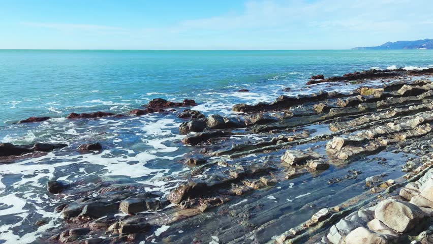 Sea waves on the Black Sea coast. Waves splash on the beach with pebbles in the rays of the sun. Sunset on the Black Sea. Panoramic view of the Black Sea. Kiseleva Rock, Russia, Agoi