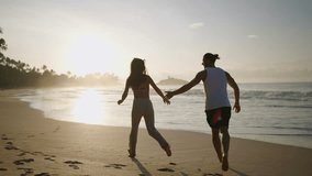 Young happy couple holding hands and running and fooling around on the beach together enjoying summer back view. Boyfriend and girlfriend having fun at the seaside chasing each other at sunrise. - Powered by Shutterstock - Get 15% off with code: PIKWIZARD15