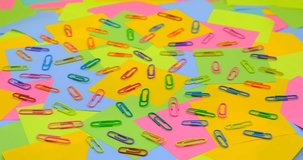 Multicolored paper clips on a rotating table with multicolored paper  