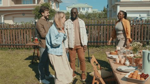 Young Black man and his girlfriend greeting their friends invited for summer bbq party at backyard Adlı Stok Video