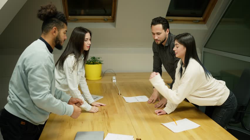 Team of entrepreneurs stacking fists to a tower in conference room