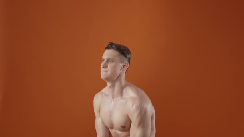 Young athlete training in the gym. Muscular man making workout and exercises. Studio lighting and cinematic look styled concept about sport and healhty lifestyle.