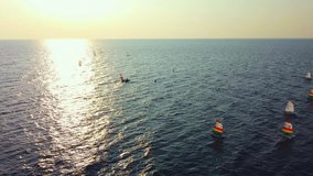 beautiful sunset on the sea, dusk, windsurfers train at sunset, small boats with sails float on the surface of the sea, the golden sun is reflected in the surface of the sea