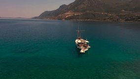 Yacht aerial drone shot around the greek islands. A rotation shot of a white yacht floating on the Aegean Sea.