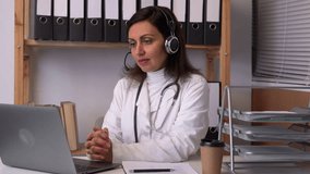 Young female doctor in telehealth concept. Doctor talking with colleagues through a video call with a laptop in the consultation.