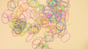 Hands taking colorful rubber bands and removing them from yellow background. Bright office rubber bands. Multicolored elastic rubber bands close up.