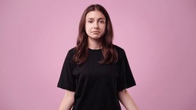 4k video of one girl with negative facial expression over pink background.