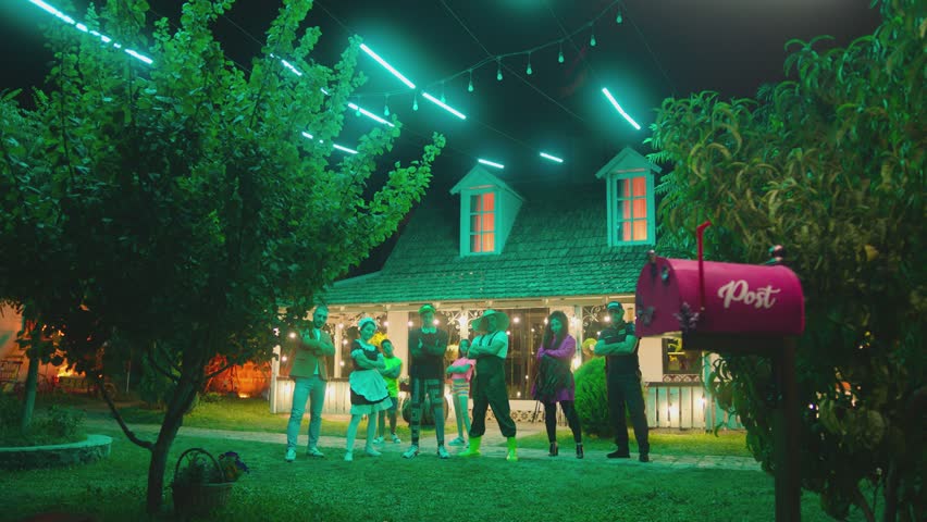 Group of funny , stylish  multi aged dancers dancing near village house at night . Kids dancing with house workers . Multi ethnic people having fun . Beautiful background with different lights . | Shutterstock HD Video #1100326177