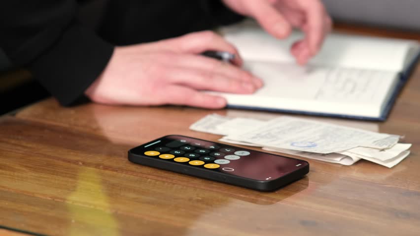 a young man in the living room sofa accounting for financial expenses and settling debts using a calculator for calculating income from financial and tax documents in the modern economy Royalty-Free Stock Footage #1100330111