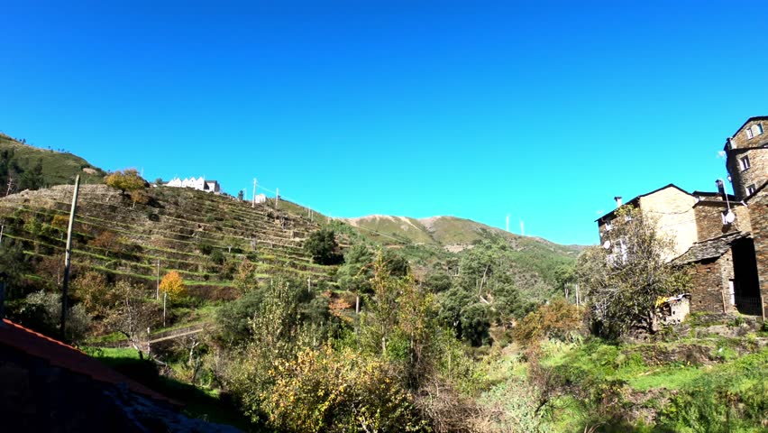 PAN SHOT SLOW MOTION - The picturesque little schist village of Piodão clings to a steeply terraced mountainside deep within the foothills of the Serra de Açor range in central Portugal.