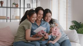 Mother's day two grown up child cuddle hug give flower gift box red heart card to mature mum. Love kiss care mom asia middle age adult three people sitting at home sofa happy smile enjoy family time. - Powered by Shutterstock - Get 15% off with code: PIKWIZARD15