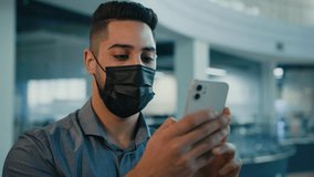 Arabian Indian ethnic businessman executive sick entrepreneur man in medical face mask holding mobile phone scrolling browsing smartphone business chatting online working using cellphone in office - Powered by Shutterstock - Get 15% off with code: PIKWIZARD15