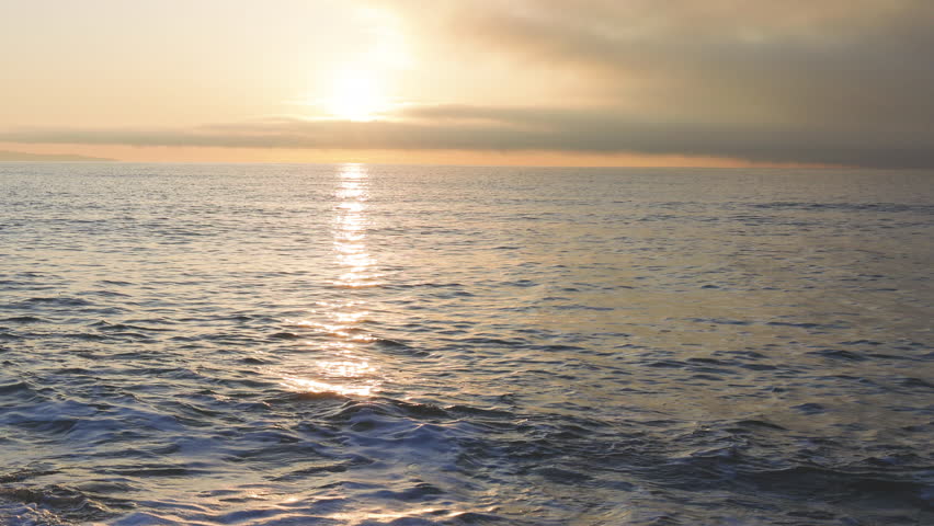 Black Sea and beach nearby against a sky with clouds and a dawn sun