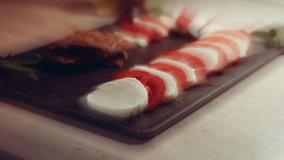 Caprese italian national dish. Sliced tomatoes and mozarella arranged in shape of Christmas candy cane. Served with basil and olive oil. Slowmotion
