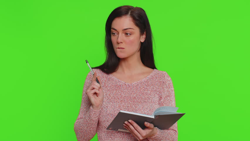 Thoughtful journalist pretty young woman in sweater making notes, writing down thoughts with pen into notepad notebook diary, to do list, good idea. Millennial girl isolated on chroma key background Royalty-Free Stock Footage #1100347333