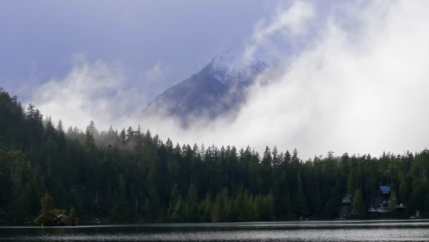 Clouds Revealing Snowy Mountain Behind Pine Tree Forest In Winter. wide