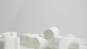 White squishy jumbo marshmallows falling onto white table top and bouncing around into a pile in slow motion - Powered by Shutterstock - Get 15% off with code: PIKWIZARD15
