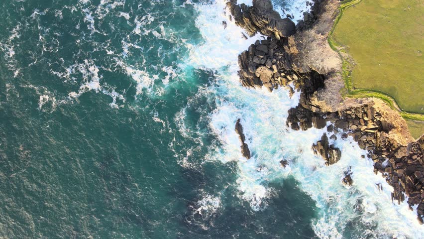 Breathtaking aerial footage captures a top down view of crashing waves in the ocean and the serene beauty of Dingle near the Great Blasket Islands on the Dingle Peninsula at golden hour.