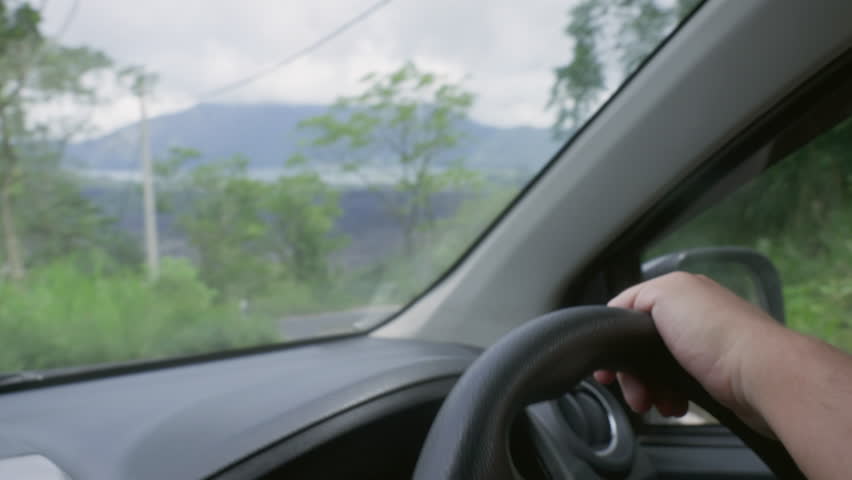 Hands on a right steering wheel driving a car on extreme road in mountains. Anonymous experienced driver on automobile trip on crazy serpentine in highlands. Travel journey around countryside in Asia. | Shutterstock HD Video #1100356701
